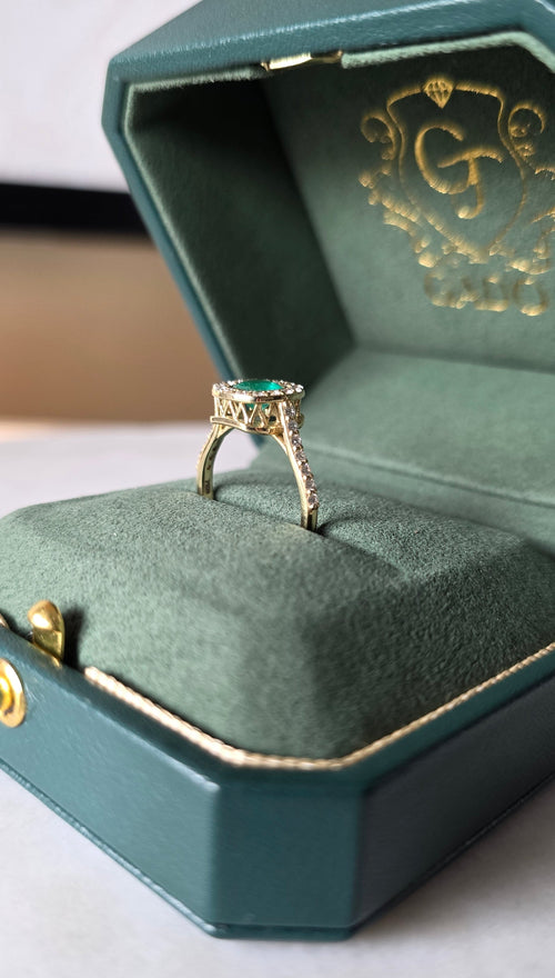 cushion cut natural colombian emerald center stone, natural diamond halo, engagement ring in 18K yellow gold, studio shot in signature Gado packaging, fully certified gemstones and gold purity | Gado Jewellers Toronto Fine Jewelry Custom Engagement Rings
