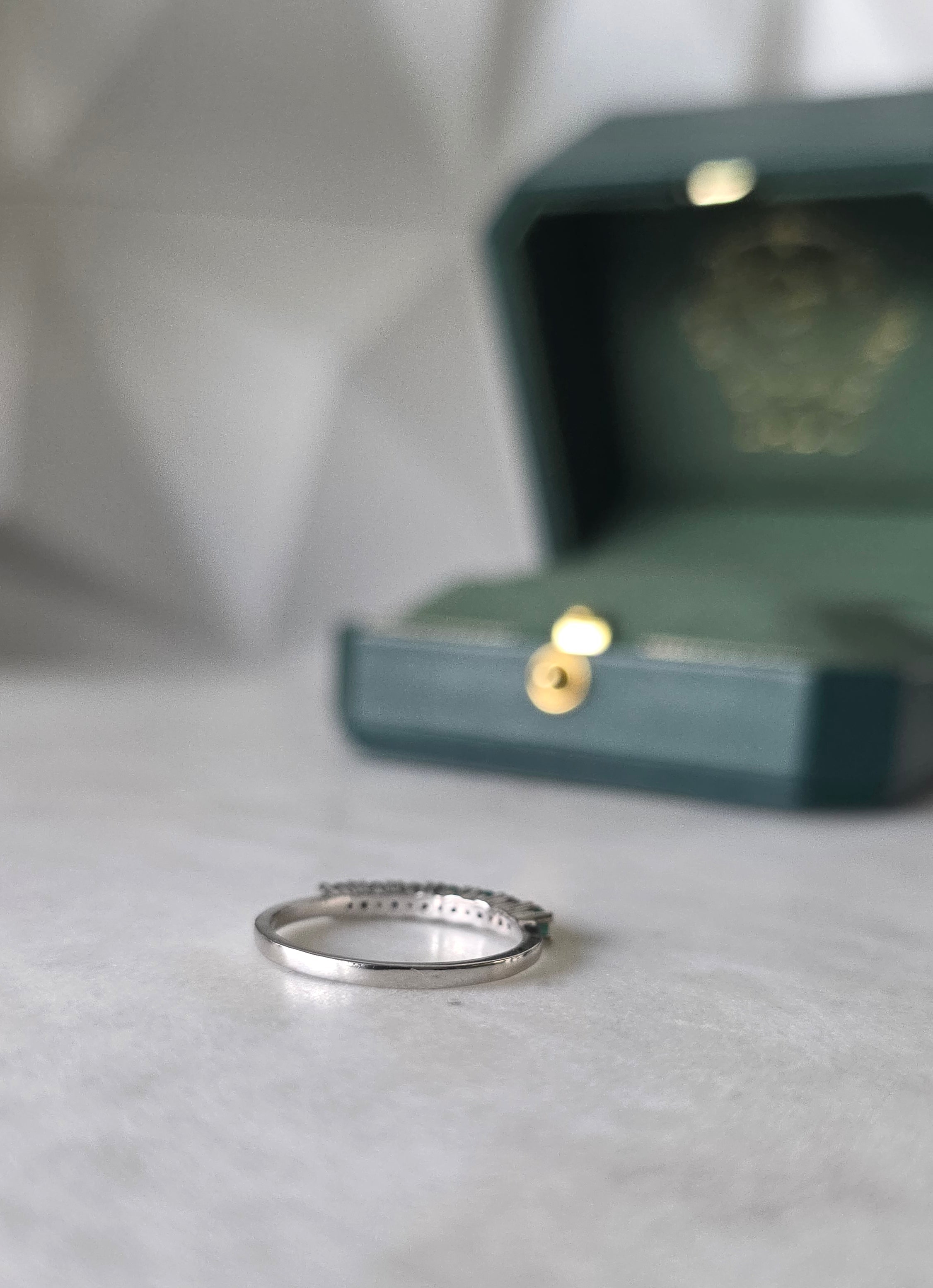 Colombian emerald band ring flat lay, round-cut emeralds, 18K white gold, Gado Jewellers