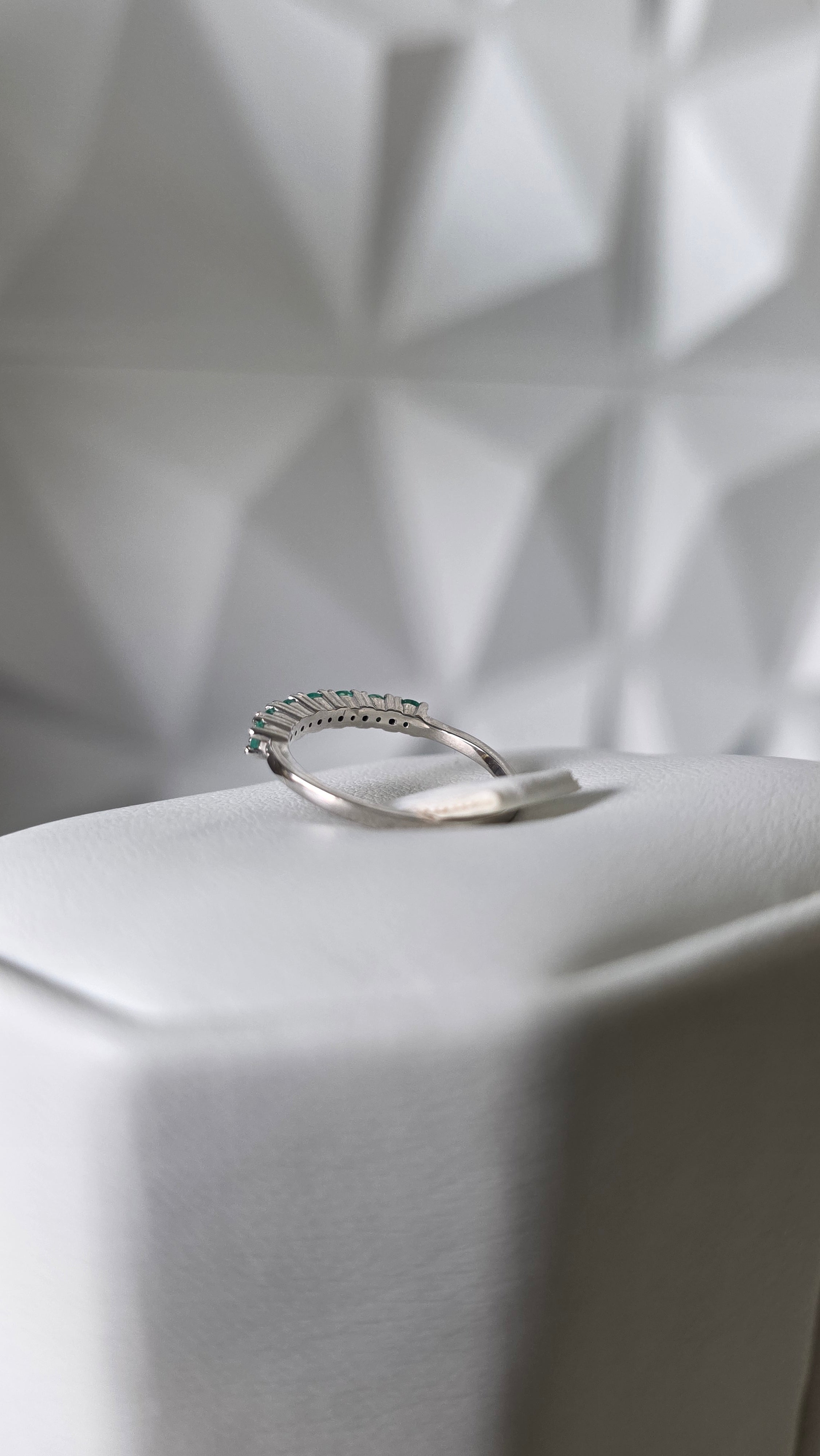 Natural Colombian emerald band ring on display stand, 18K Italian white gold, Gado Jewellers