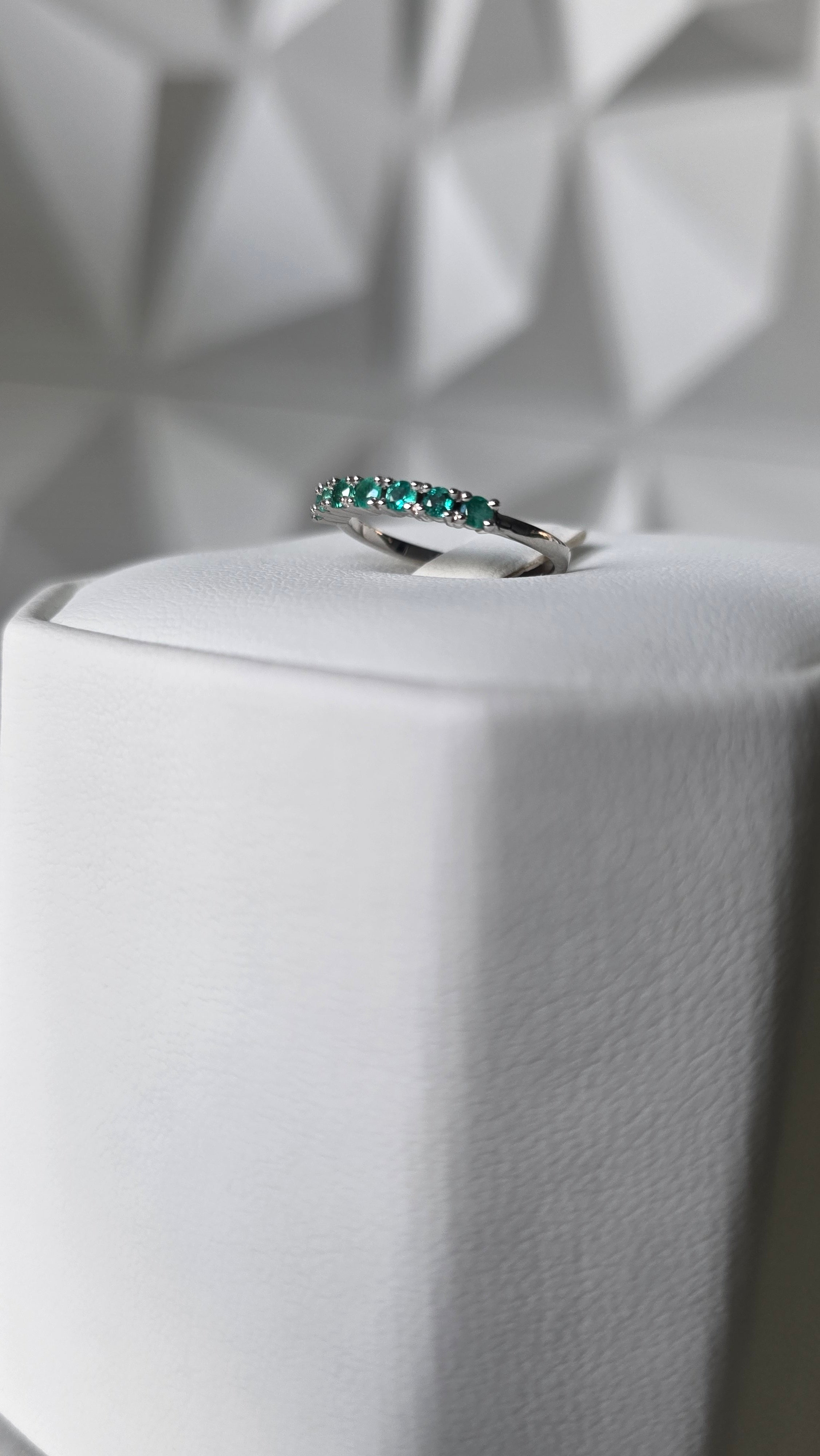 Natural Colombian emerald band ring on display stand, 18K Italian white gold, Gado Jewellers
