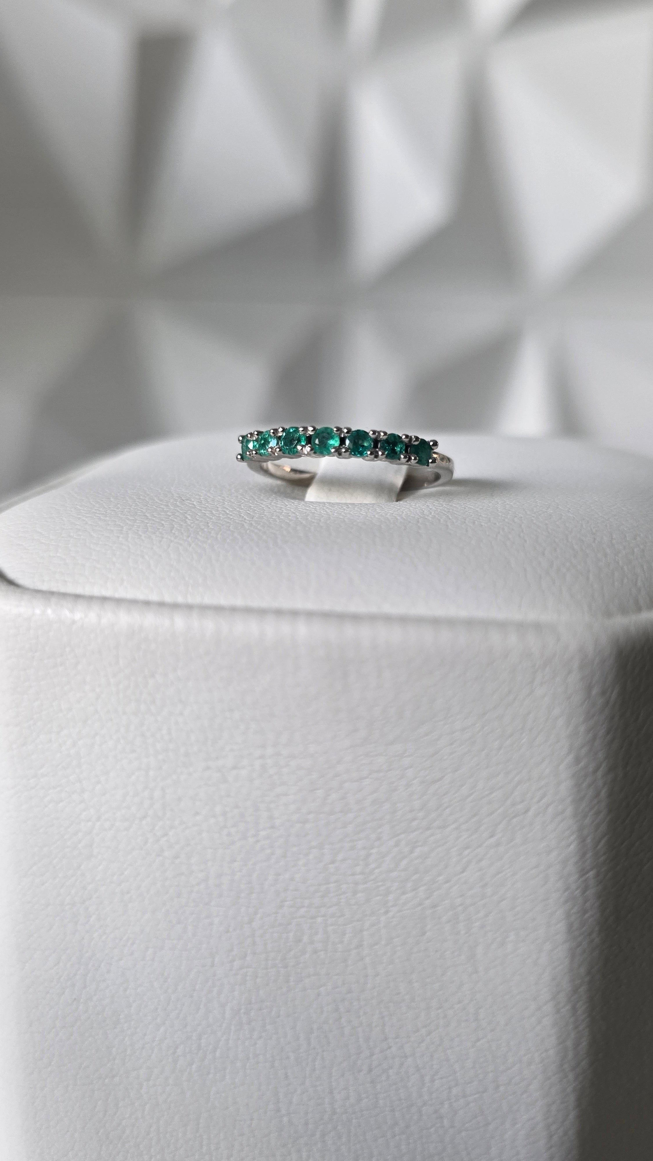Natural Colombian emerald band ring on display stand, 18K Italian white gold, Gado Jewellers