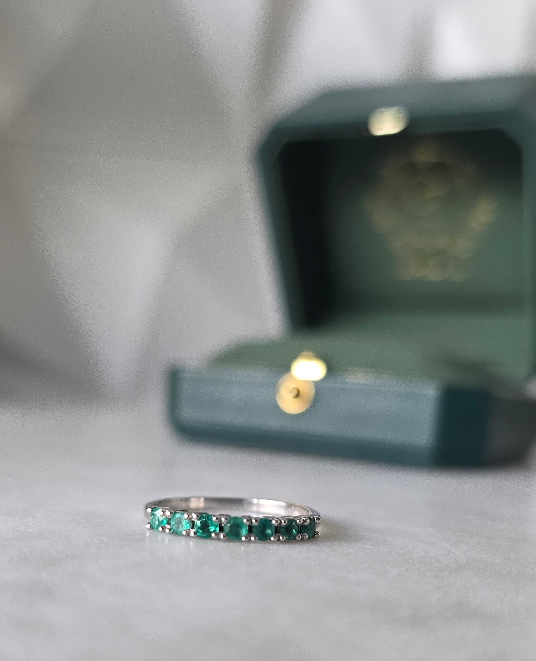 Colombian emerald band ring flat lay, round-cut emeralds, 18K white gold, Gado Jewellers