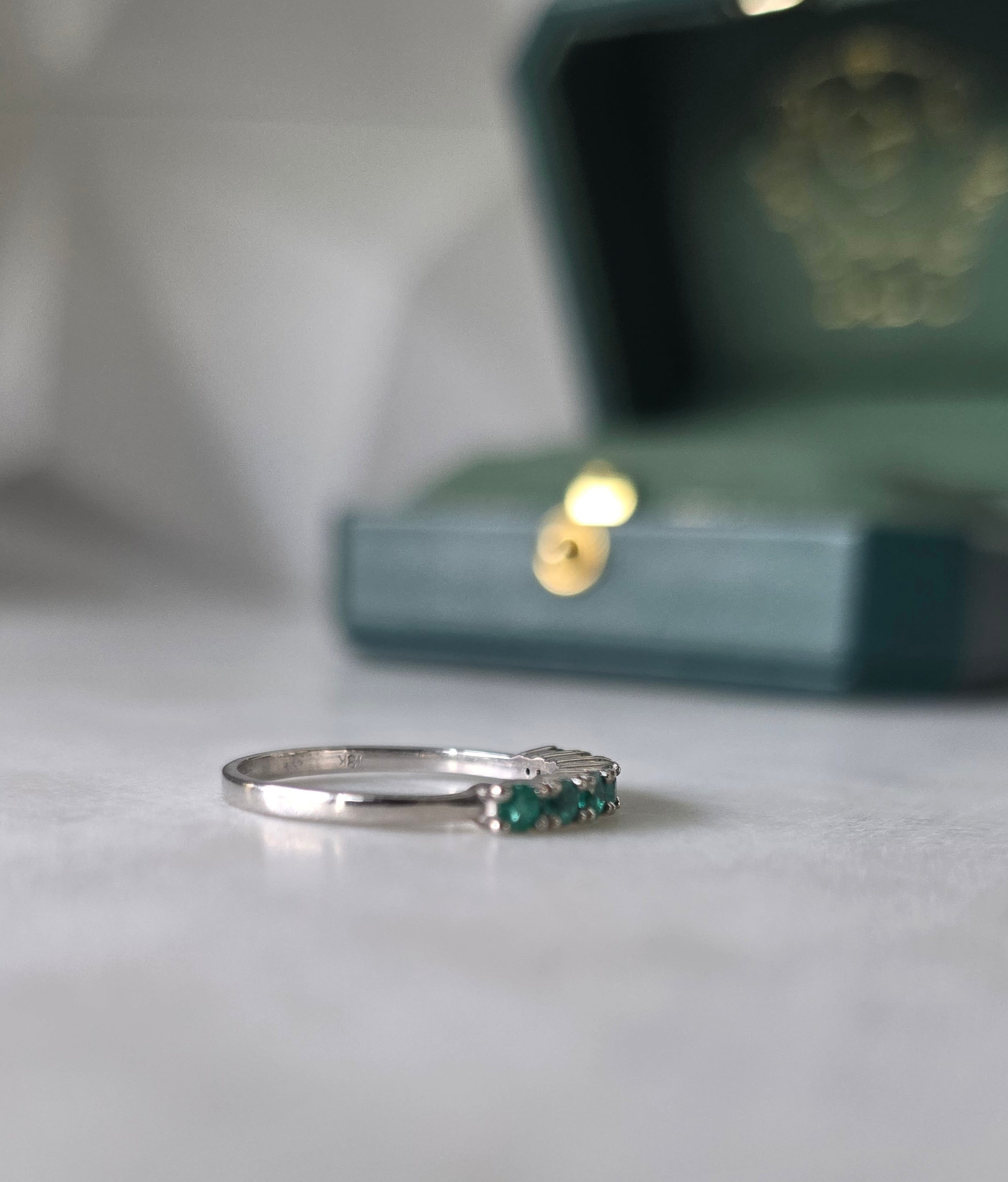 Colombian emerald band ring flat lay, round-cut emeralds, 18K white gold, Gado Jewellers