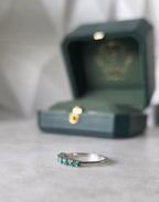 Colombian emerald band ring flat lay, round-cut emeralds, 18K white gold, Gado Jewellers