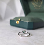 Side profile of Colombian emerald diamond halo ring in 18K white gold by Gado Jewellers